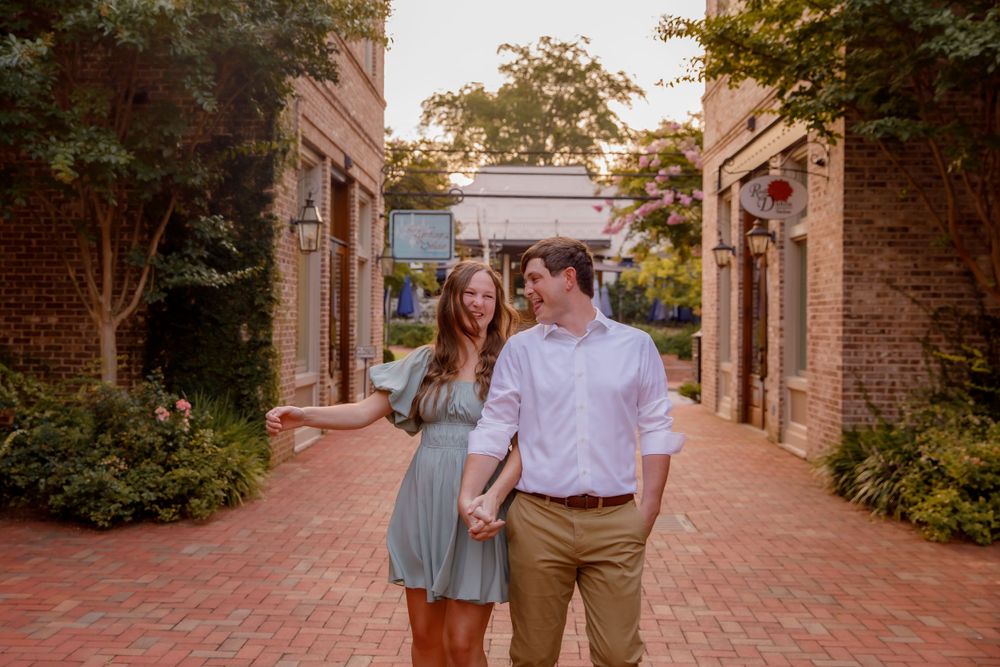 A couple shares a casual moment together in a brick-lined courtyard during an engagement photoshoot.