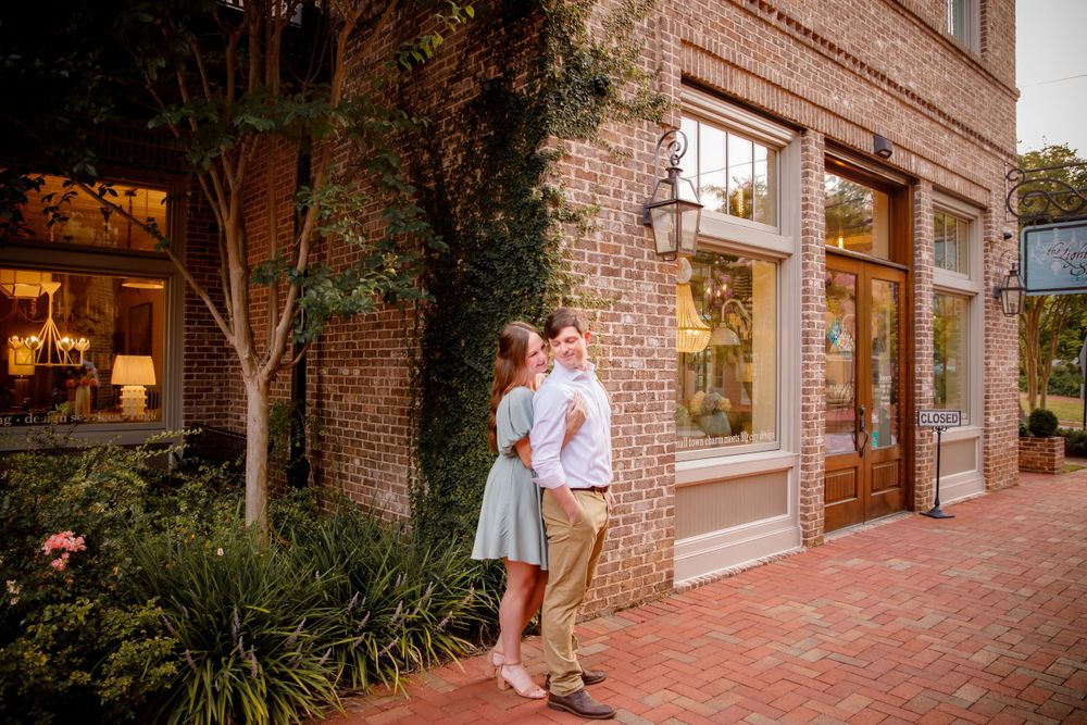 A romantic moment between a couple outside a brick storefront with garden planters.