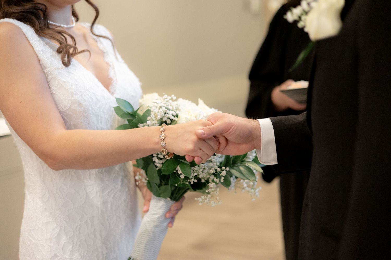 A close-up shot of hands exchanging wedding rings during a ceremony with a white bouquet.