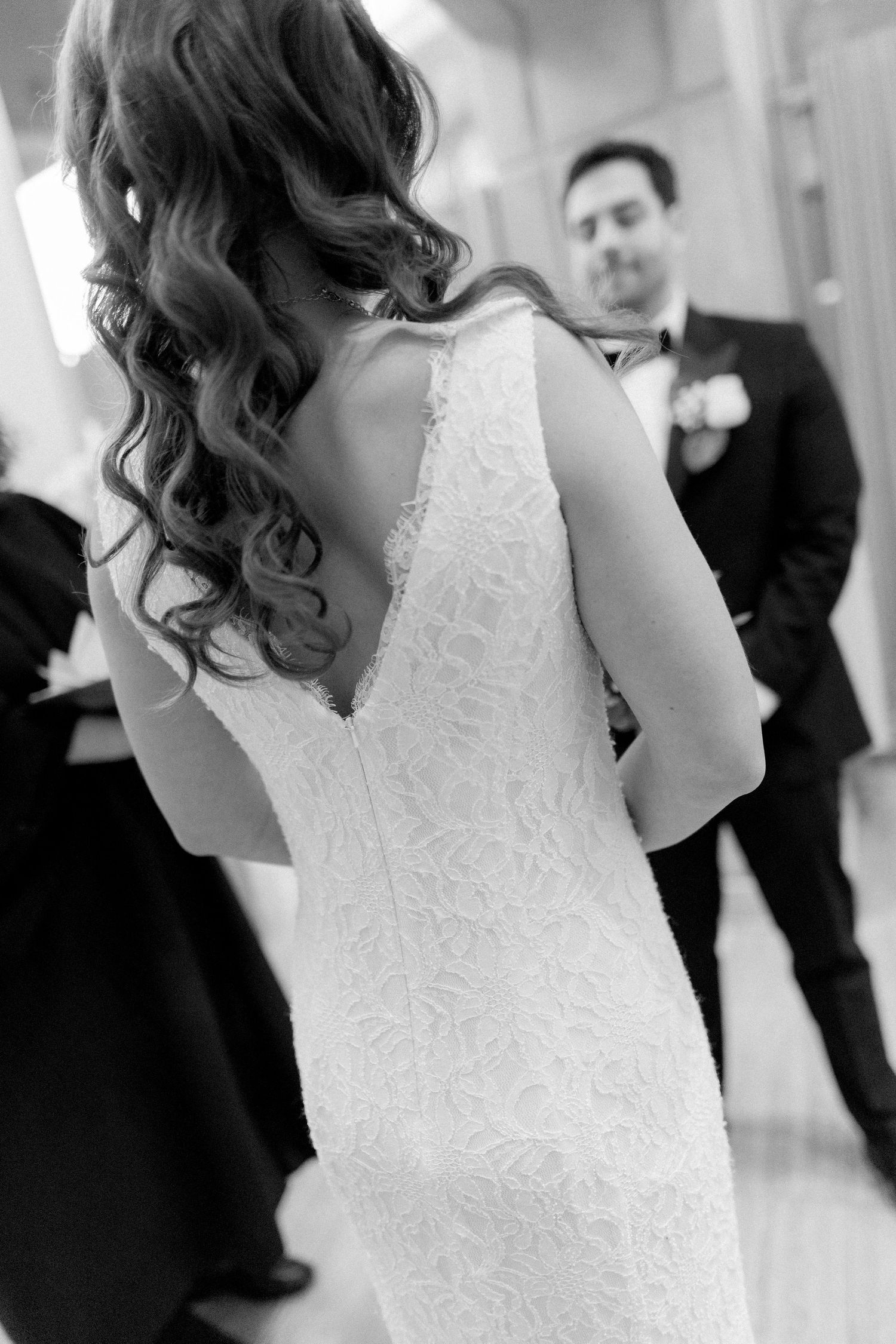 Black and white photo showing intricate lace details of a wedding dress.