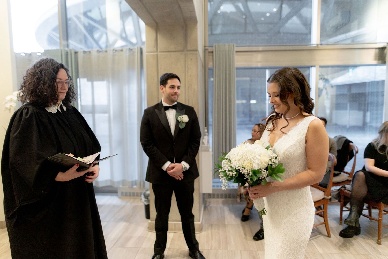 An intimate wedding ceremony takes place in a modern indoor venue.