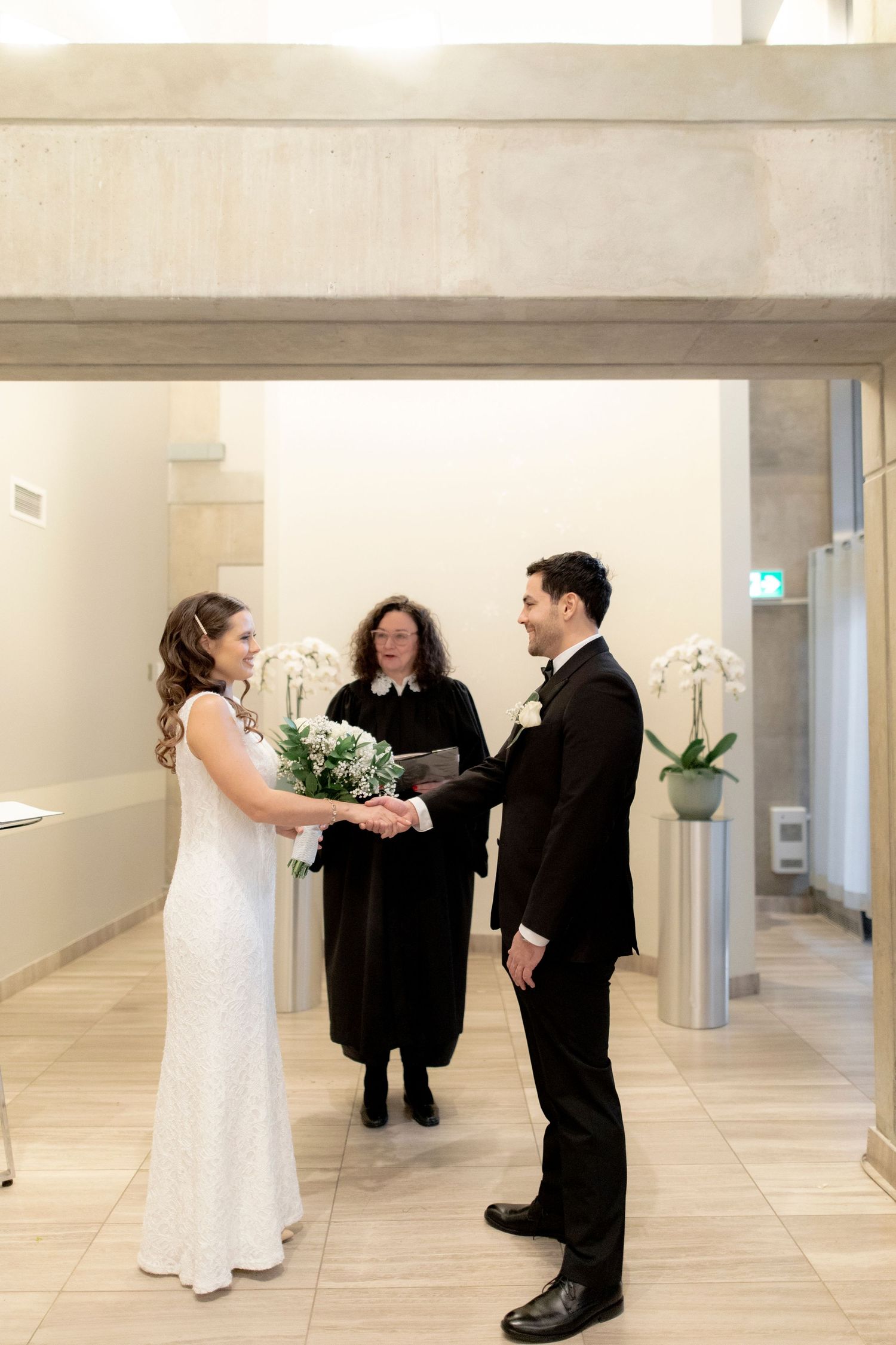 An intimate wedding ceremony with officiant in a minimalist modern hallway setting.