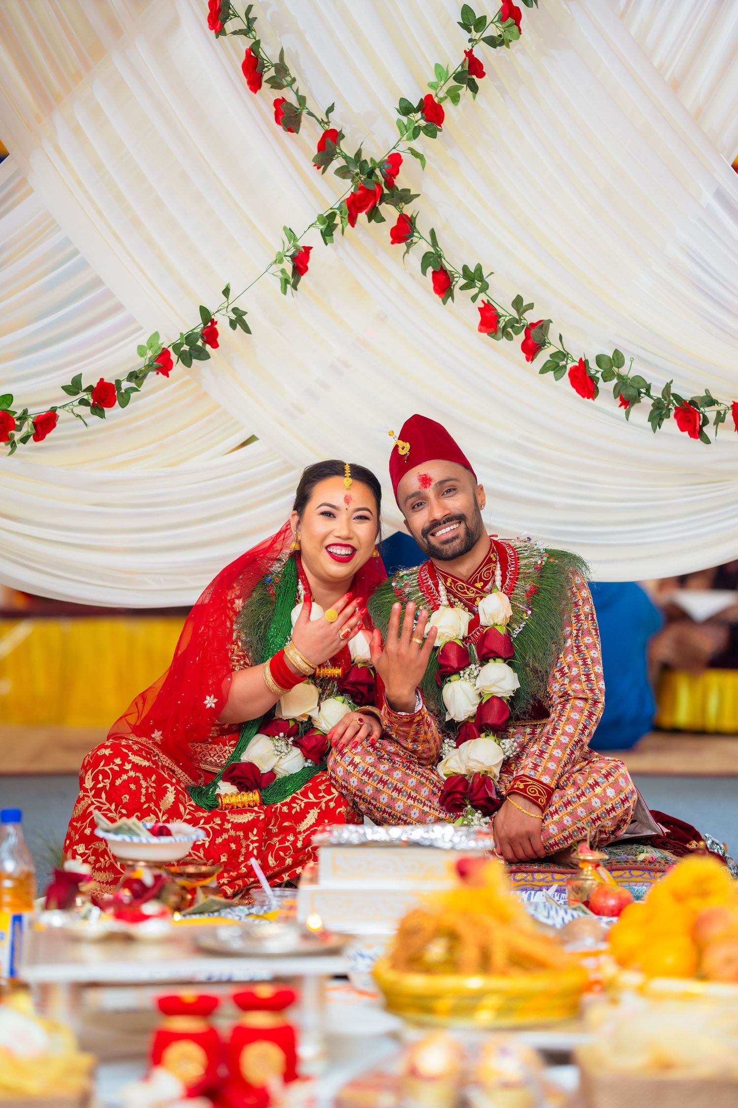 Traditional Hindu wedding ceremony with couple seated under floral decorated mandap with festive decorations.