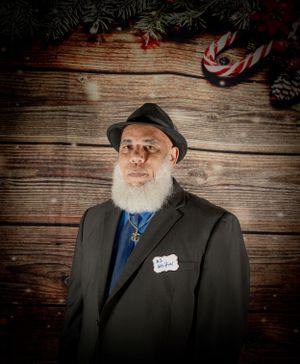 Portrait of distinguished gentleman in suit and hat against rustic wooden background.