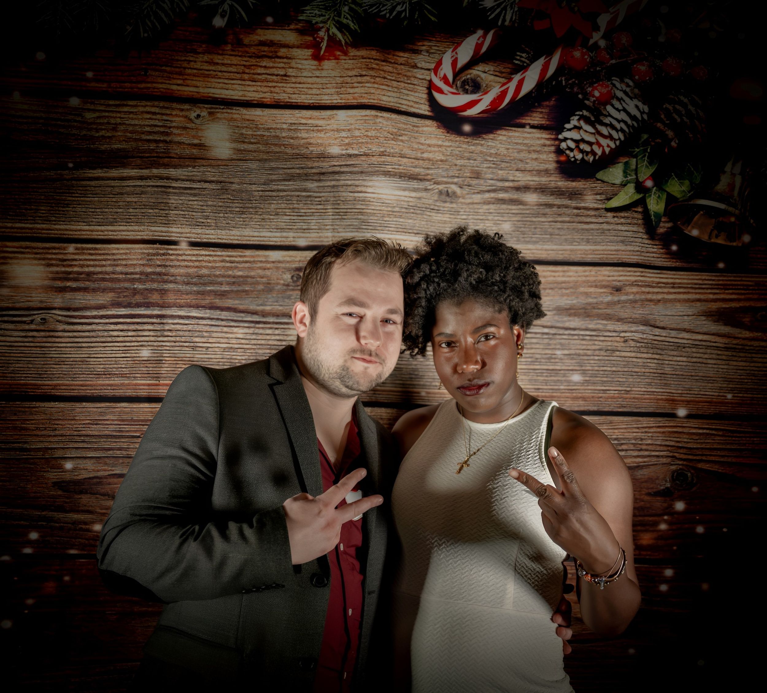 Portrait of couple posing together against wooden backdrop with holiday decor.