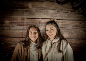 People pose against rustic wooden wall backdrop in warm lighting at holiday gathering.