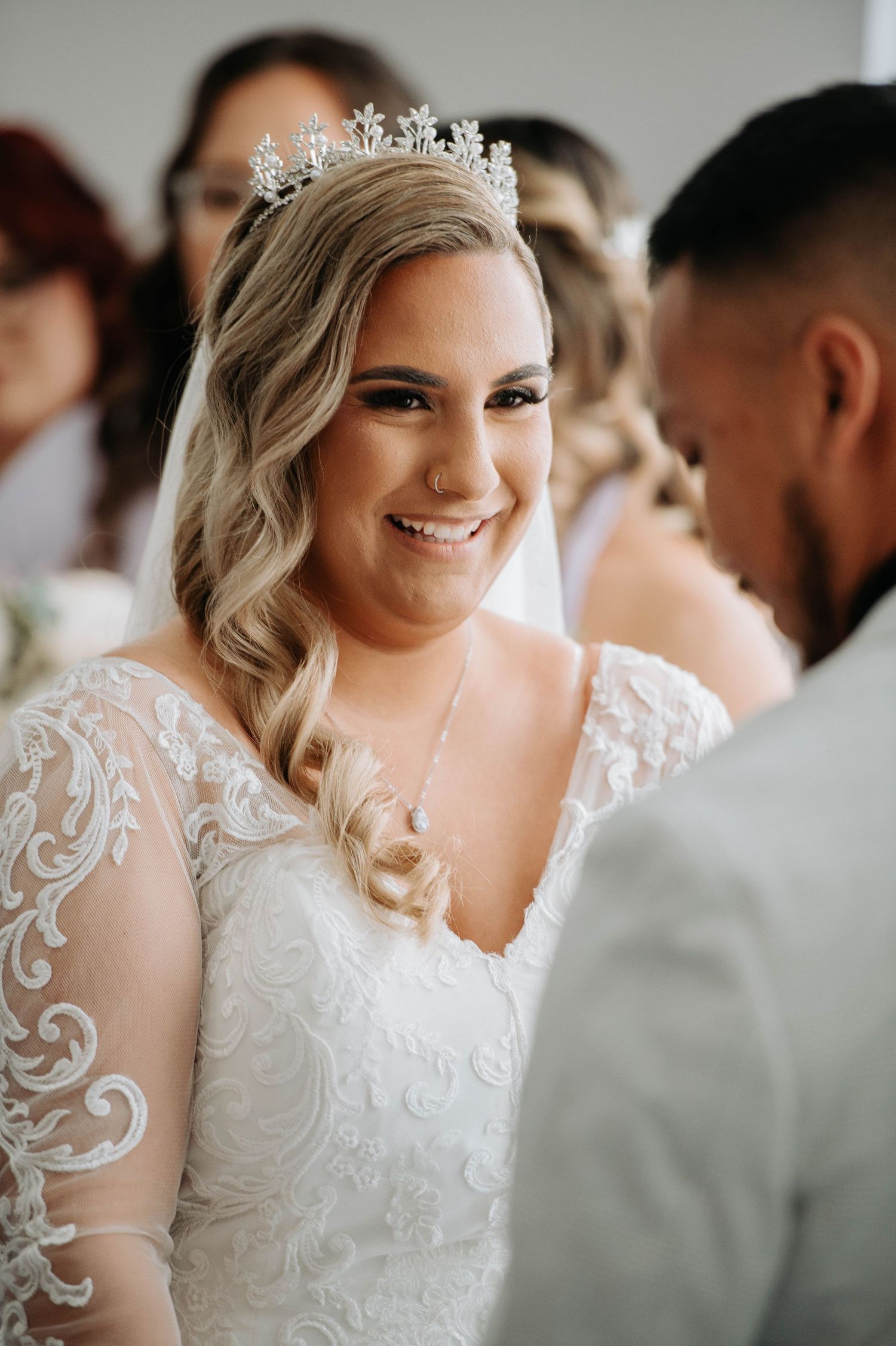 Close-up of a bride wearing a crystal crown and lace dress during her wedding ceremony.