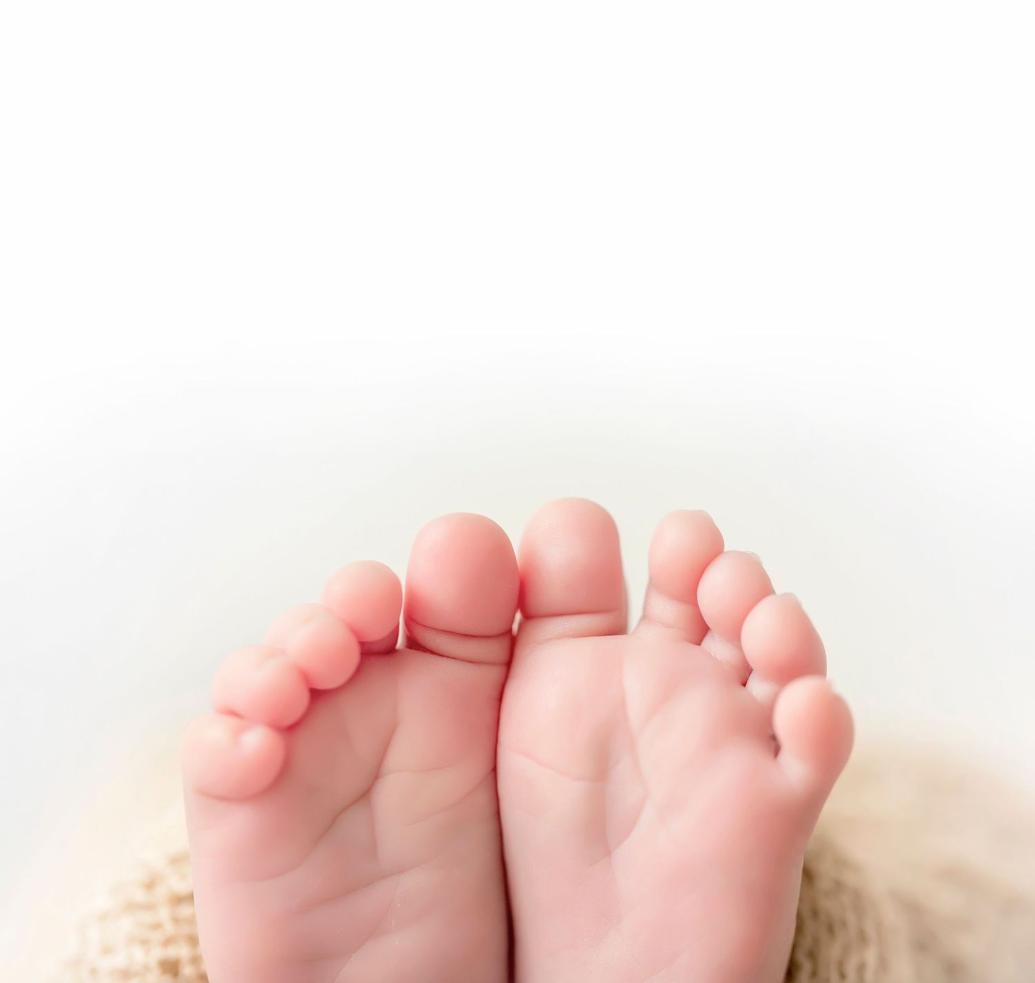 Tiny newborn baby feet photographed against a soft white background at the Clear Lake Iowa newborn photography studio.