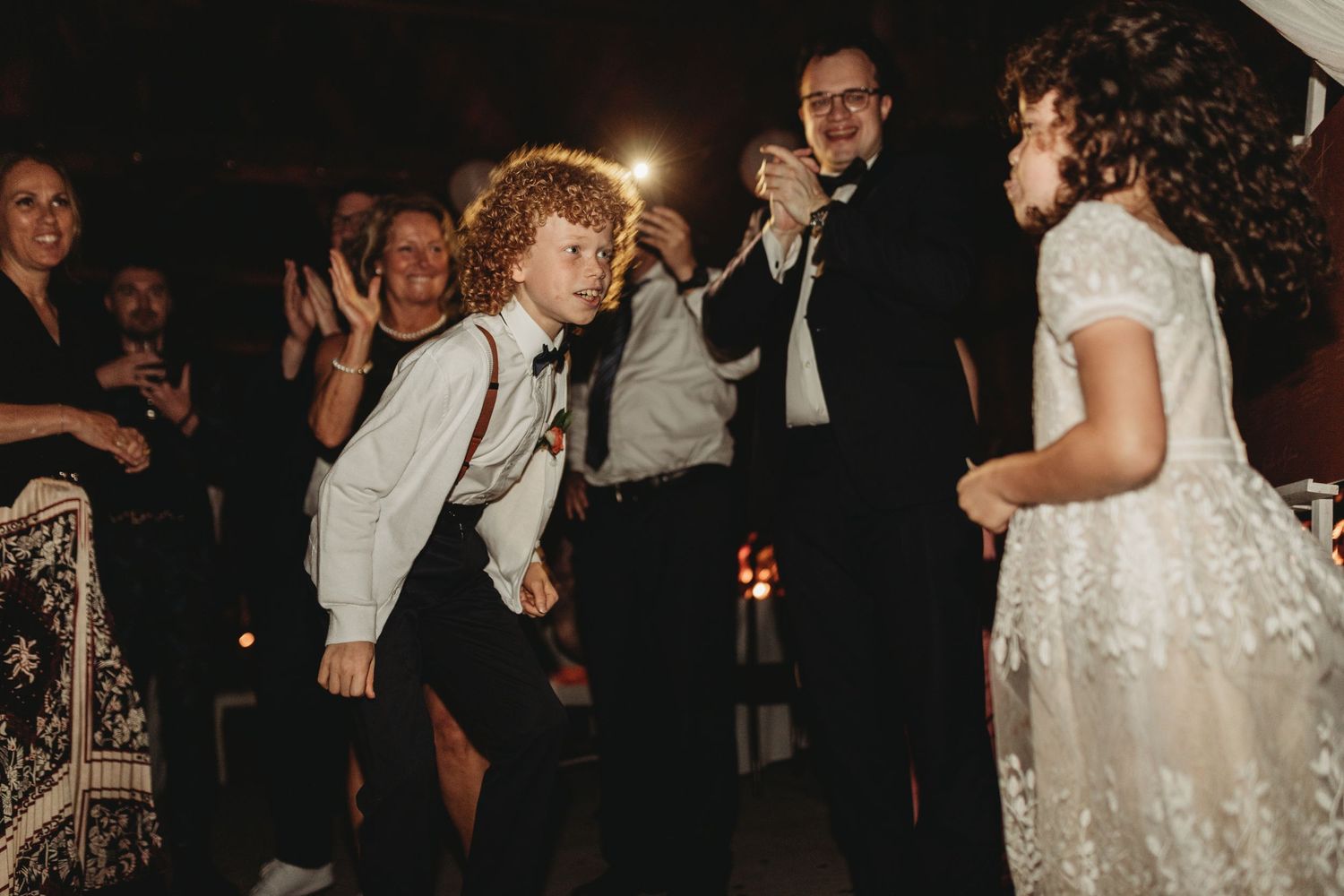 Guests dancing and celebrating at a wedding reception in a dimly lit venue.
