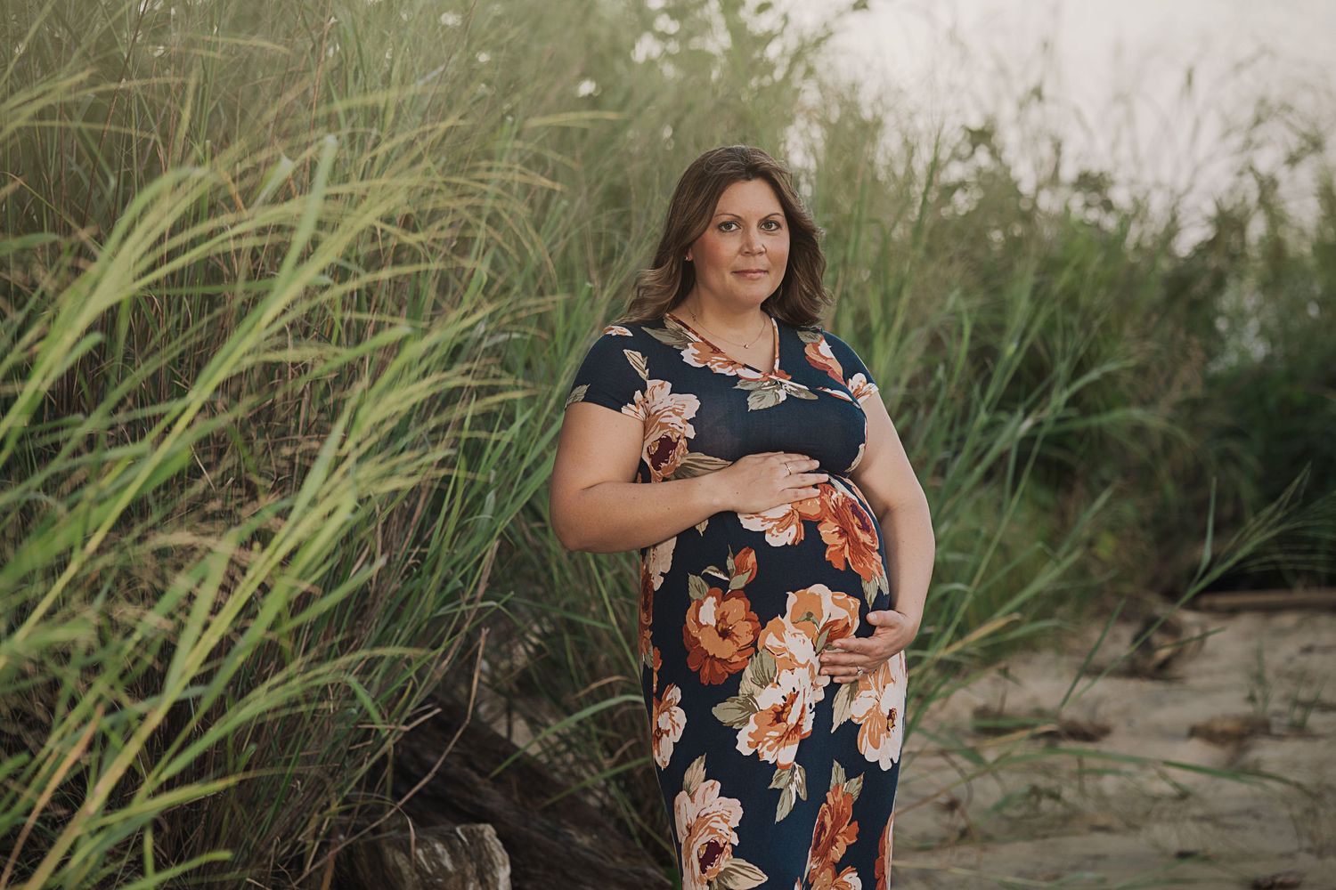 Portrait session in natural setting with tall grass and soft evening light.