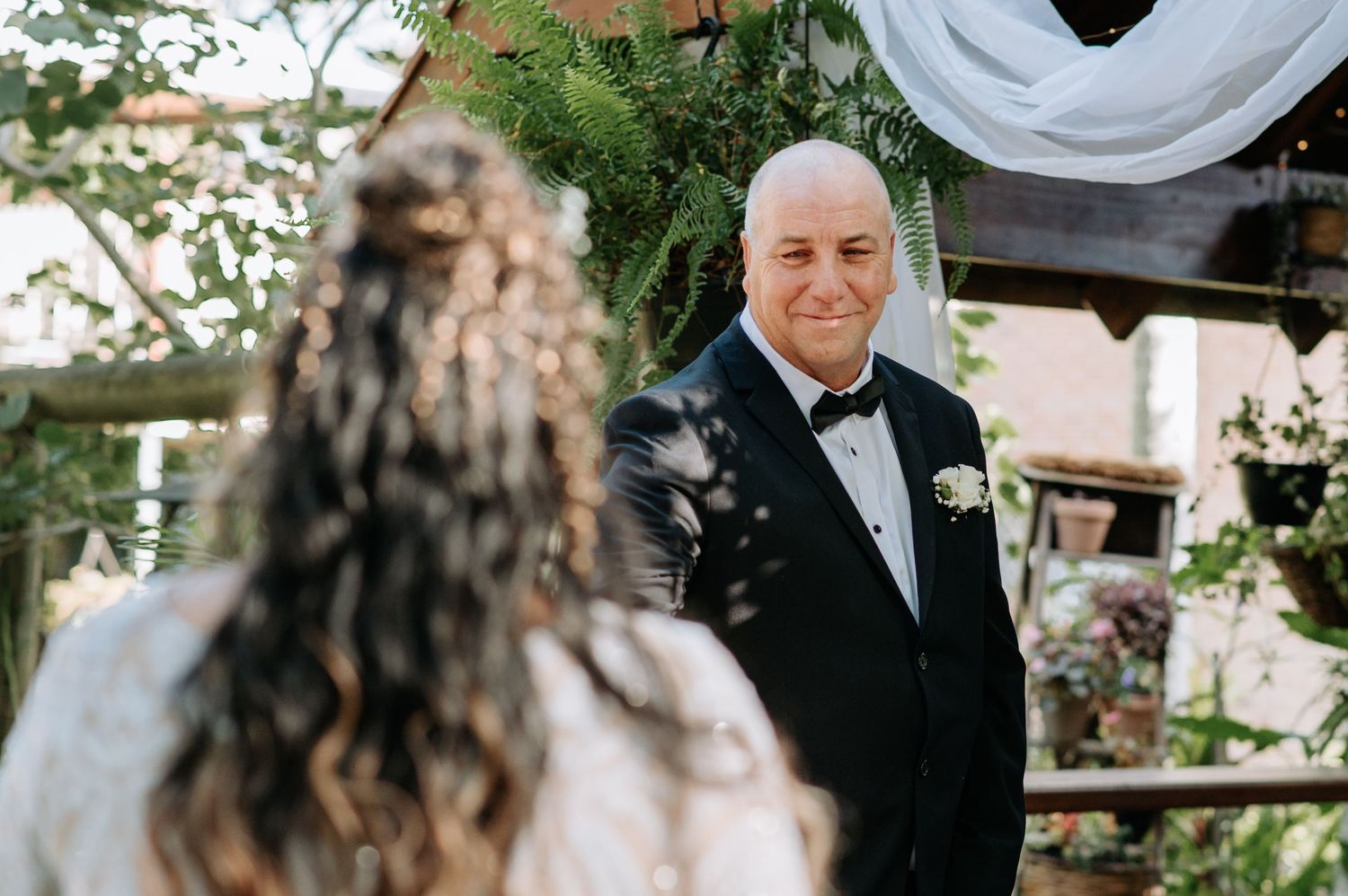 Groom in tuxedo during outdoor wedding ceremony.