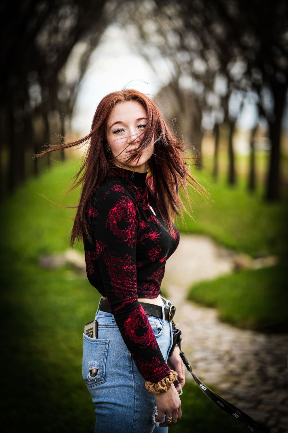 A burgundy patterned sweater creates contrast against a blurred green nature background.