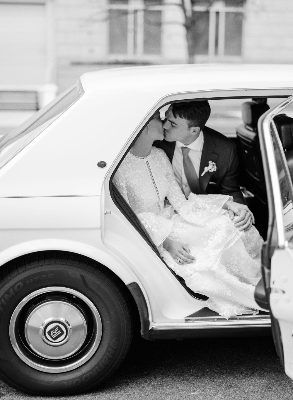 Wedding couple sitting in a classic white car after their ceremony.