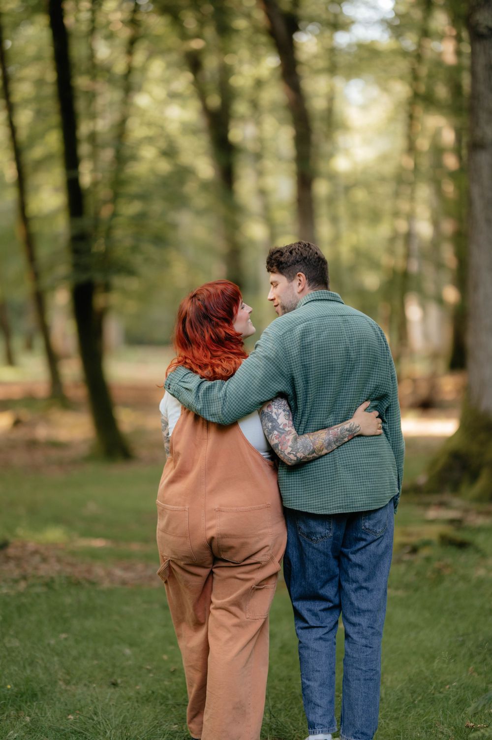 A couple embraces while walking through a peaceful wooded area on a sunny afternoon.