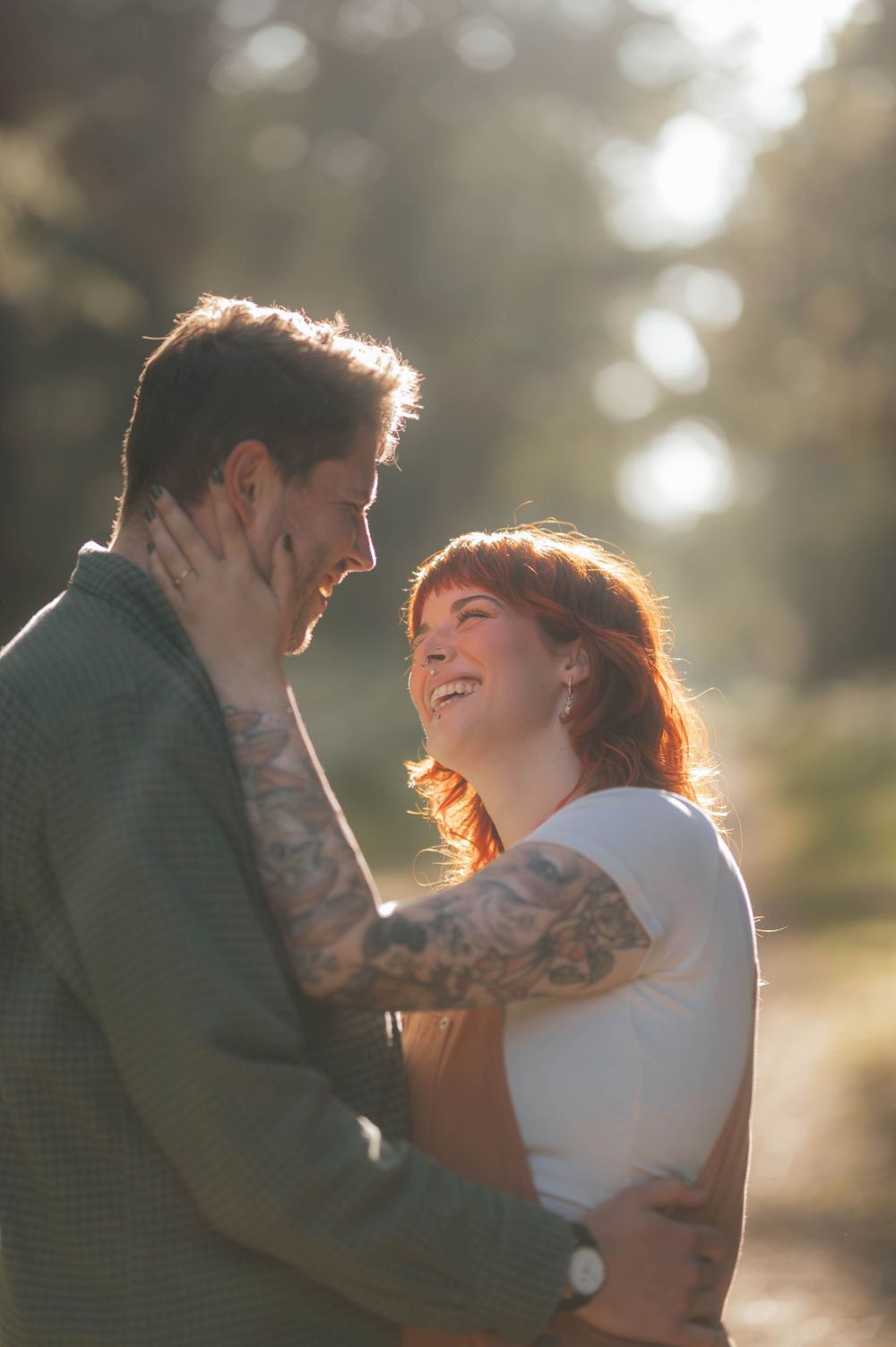 A couple embraces in soft golden sunlight creating a romantic atmosphere with dreamy bokeh background.