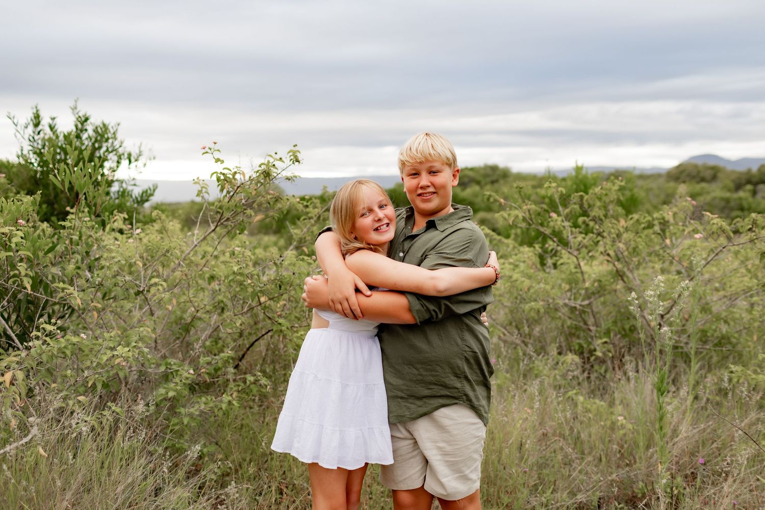 Sweet embrace captured in natural desert setting with overcast sky.