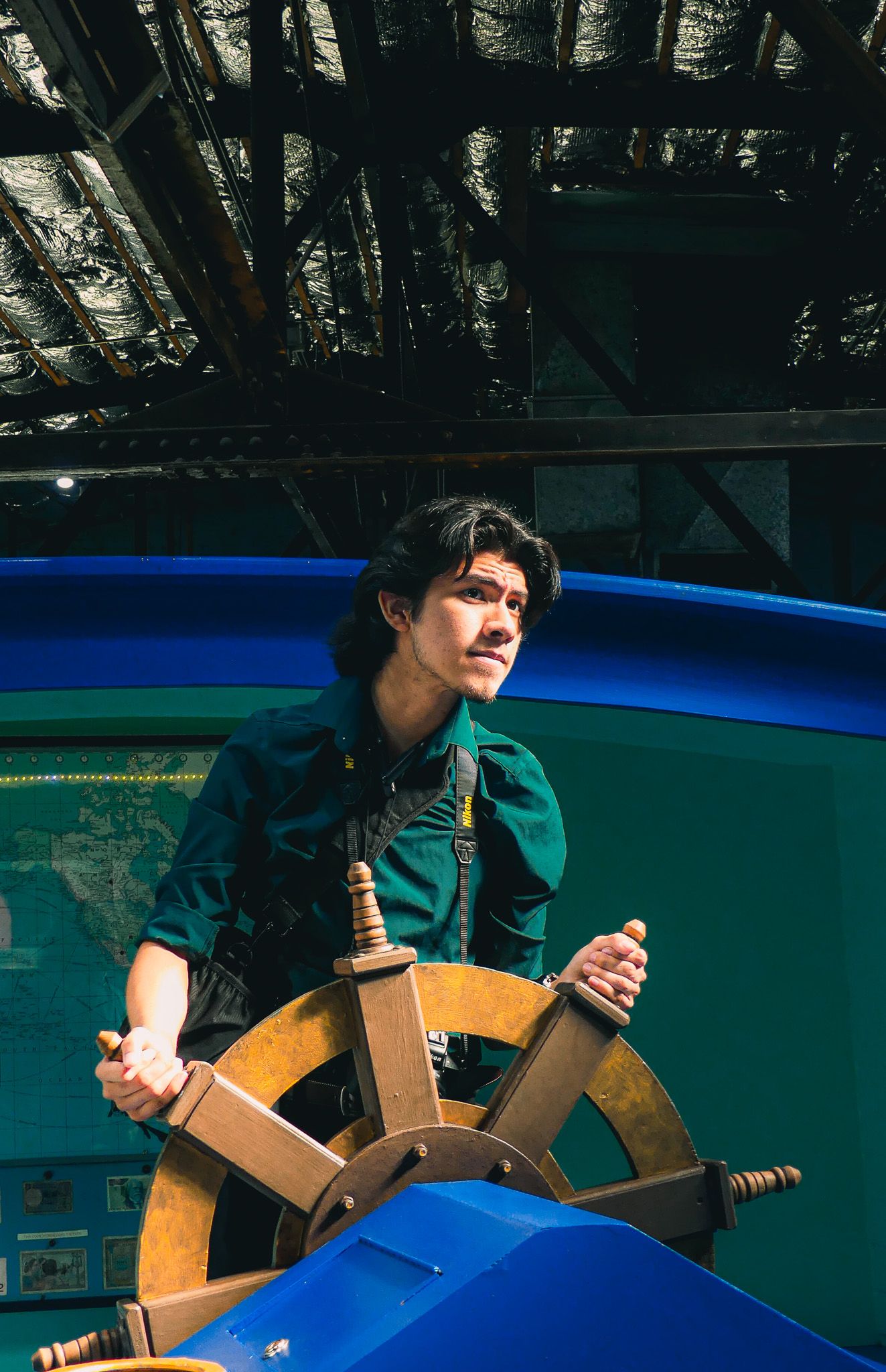 Person using a wooden climbing structure in a blue pool setting.