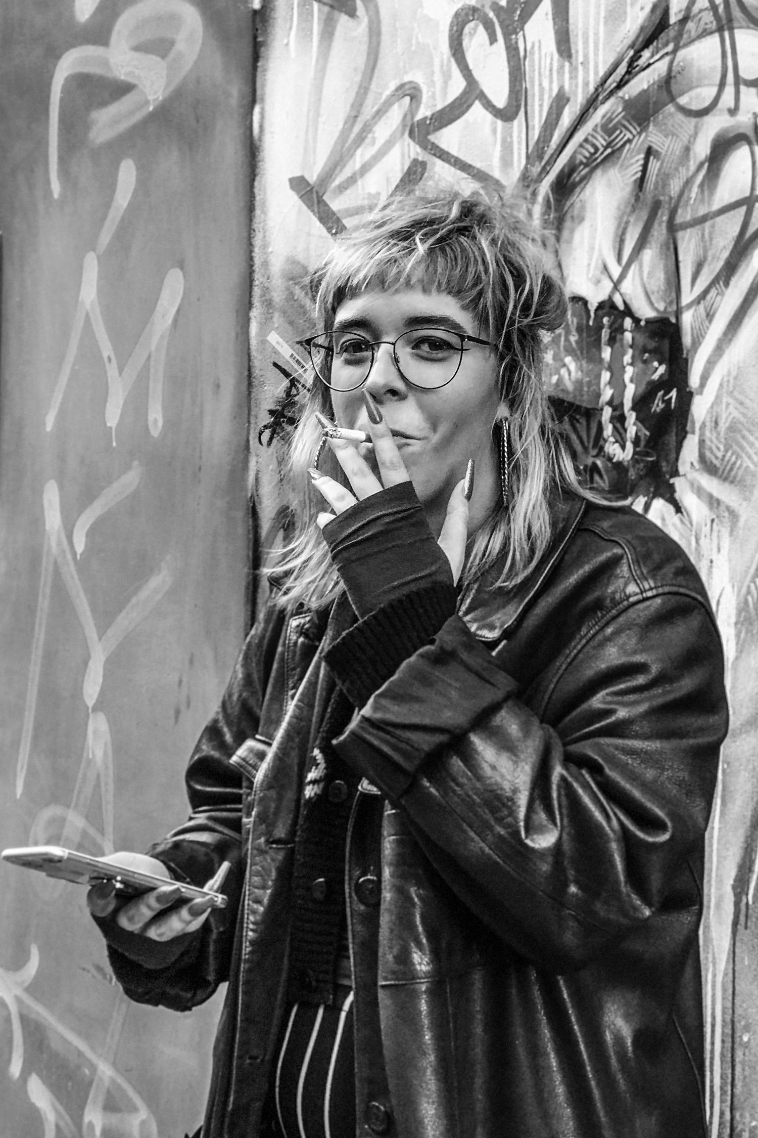 Black & White Portrait of a Stranger young woman with long nails smoking a cigarette looking directly at the camera