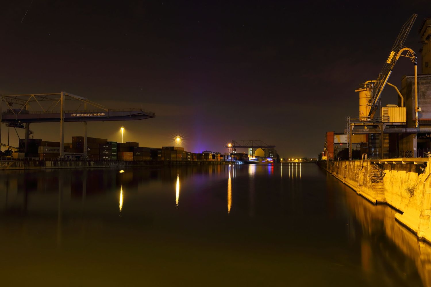 Harbor cranes and industrial structures silhouetted against a dark waterfront.