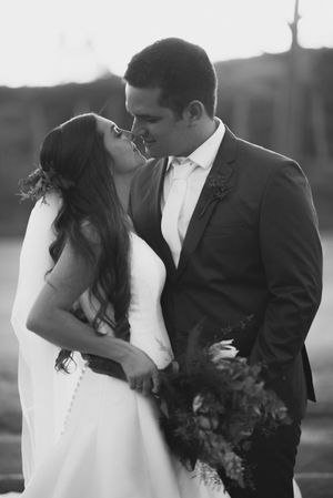 An intimate black and white portrait of newlyweds sharing a romantic moment outdoors.