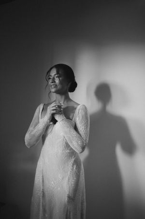 A dramatic black and white bridal portrait with a striking shadow cast on the wall.