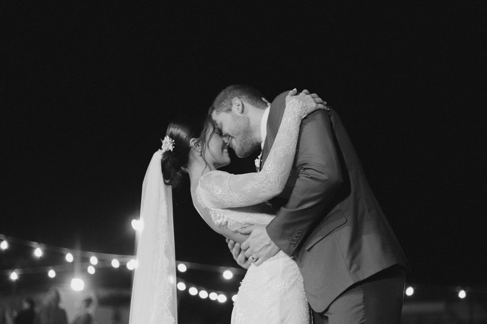 A romantic black and white wedding photo of a couple's intimate dance under twinkling lights.