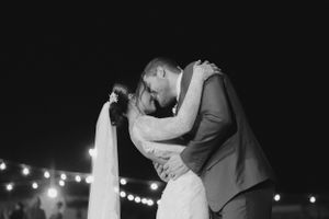 A romantic black and white wedding photo of a couple's intimate dance under twinkling lights.