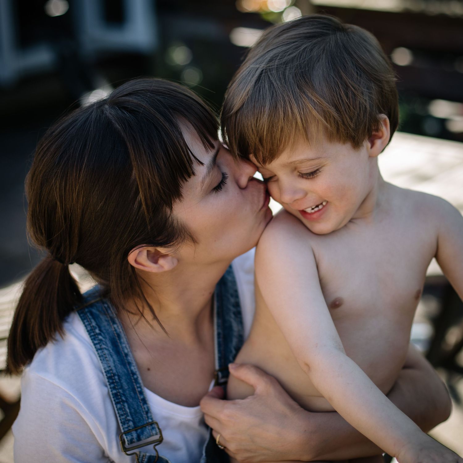 An intimate moment of affection and laughter shared in warm sunlight.