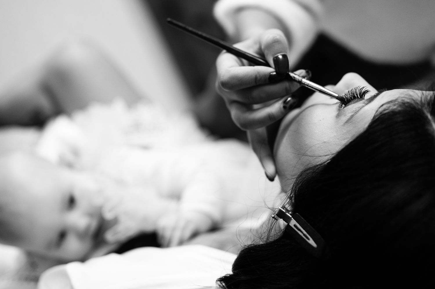 Close-up black and white image of eyelash extension application process.