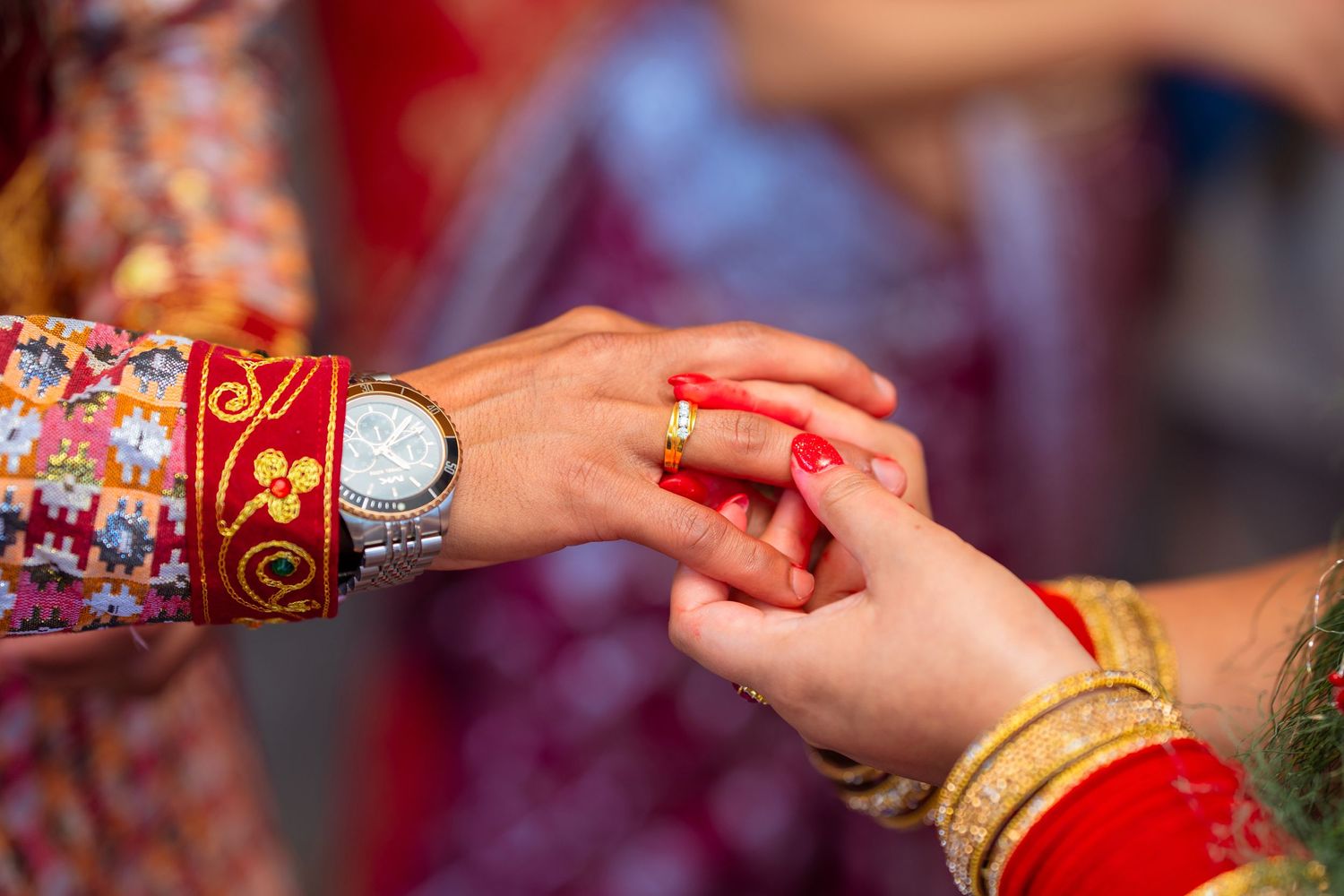 Detail shot of hands during traditional ring ceremony with bangles and henna decoration.