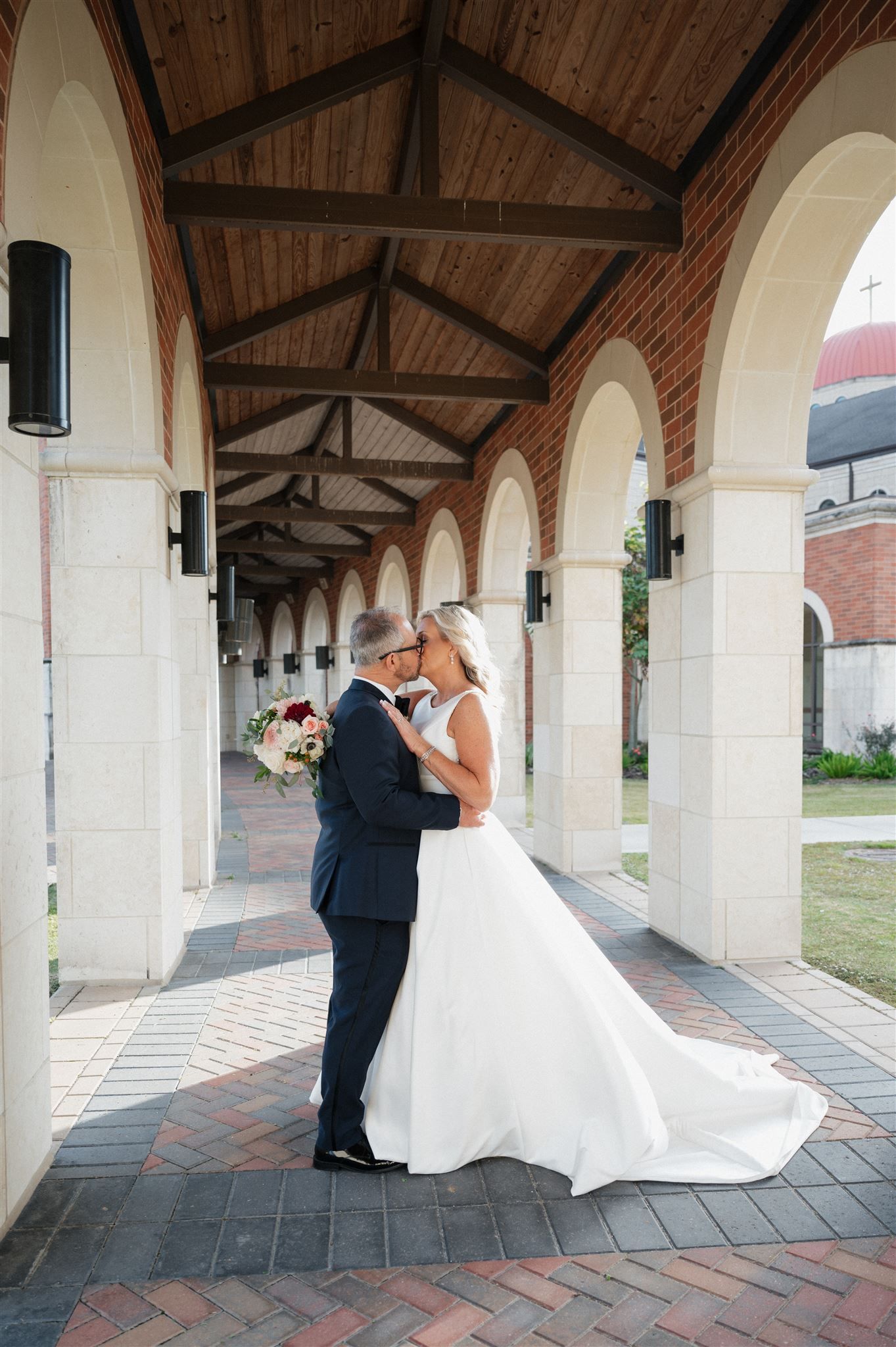 Wedding couple shares intimate moment under wooden beam archway.
