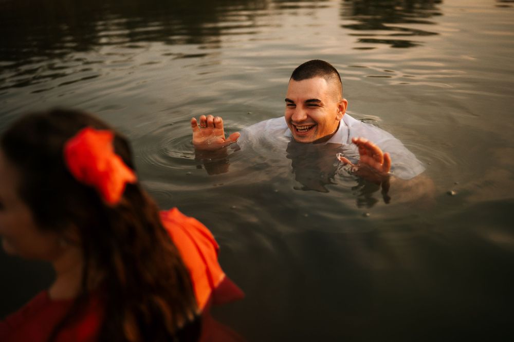A playful moment captured in the water during sunset with red dress and white shirt visible.