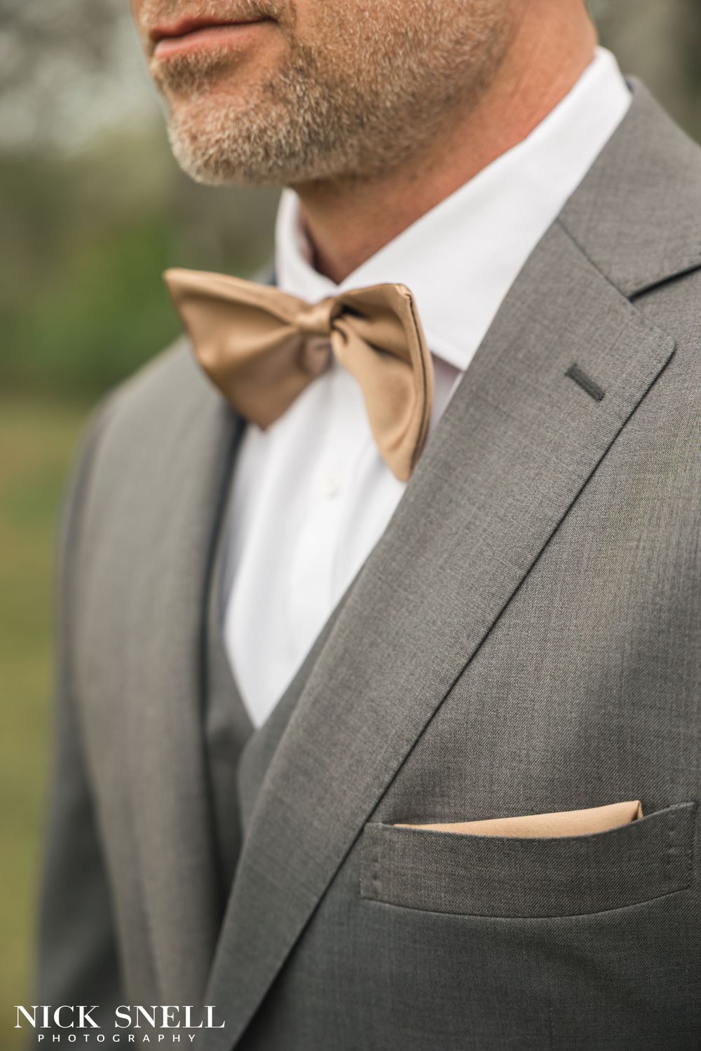 Close-up details of gray suits with tan bow ties and pocket squares.