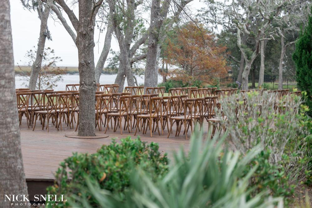 Rustic wooden boardwalk winds through trees and palm trees at an outdoor wedding venue.