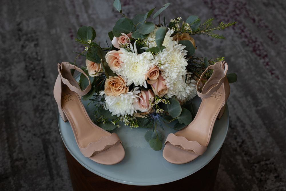 Bridal bouquet with blush roses and white flowers next to nude heels.