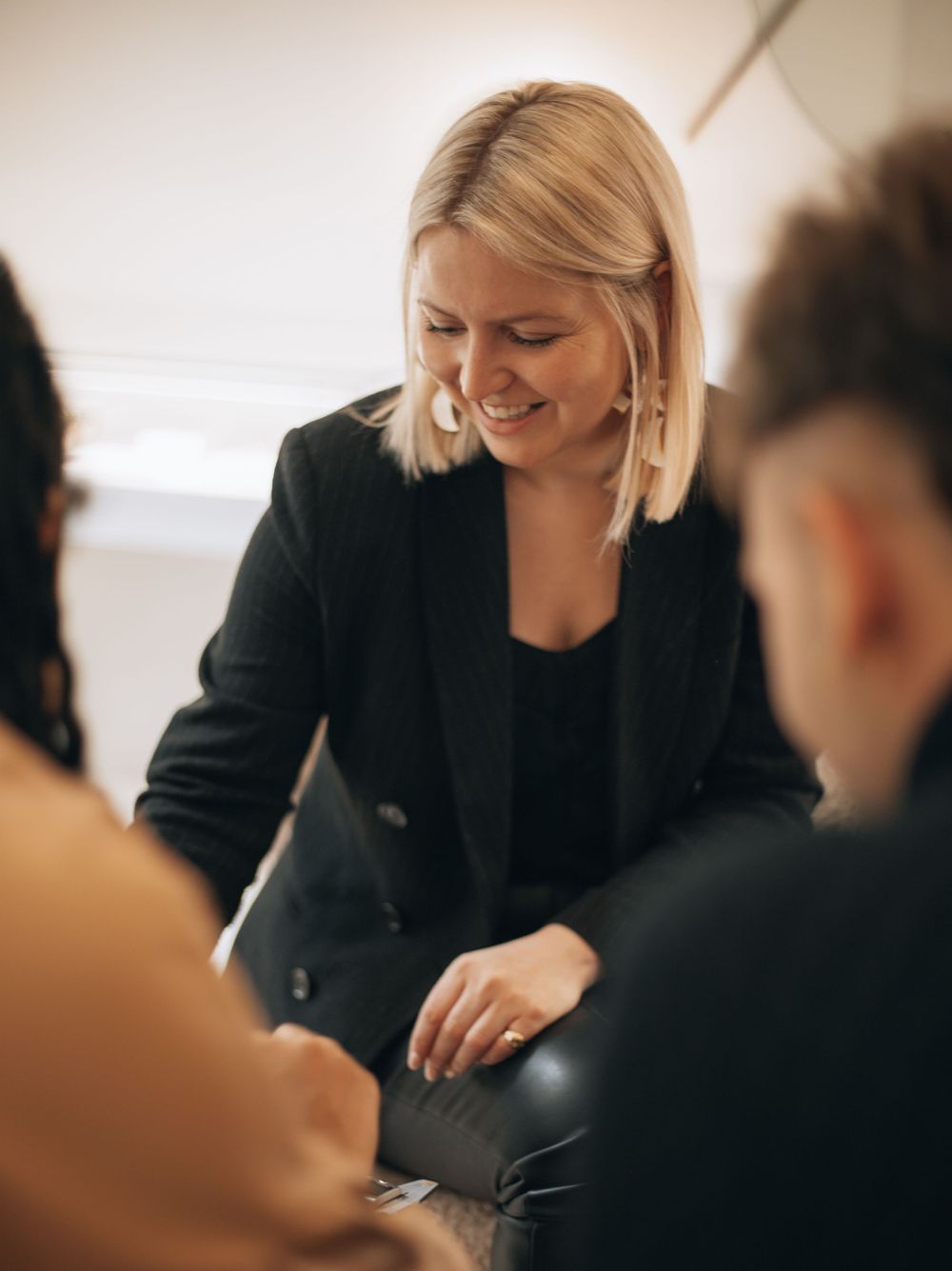 People gathered around a table in a casual business meeting wearing dark clothing.