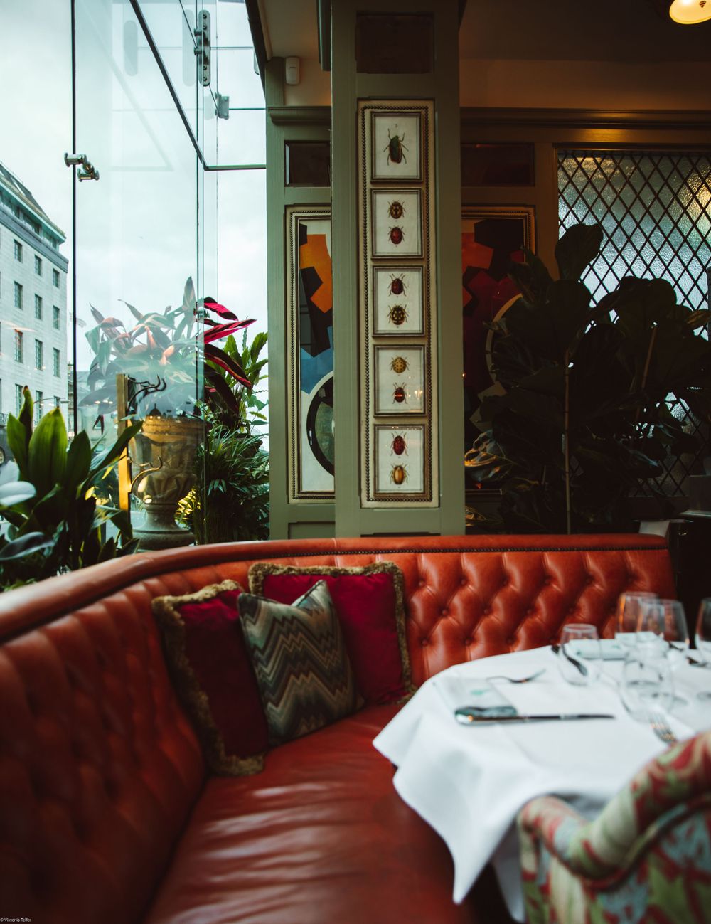 Luxurious restaurant interior with red leather booth seating and framed artwork on the walls.