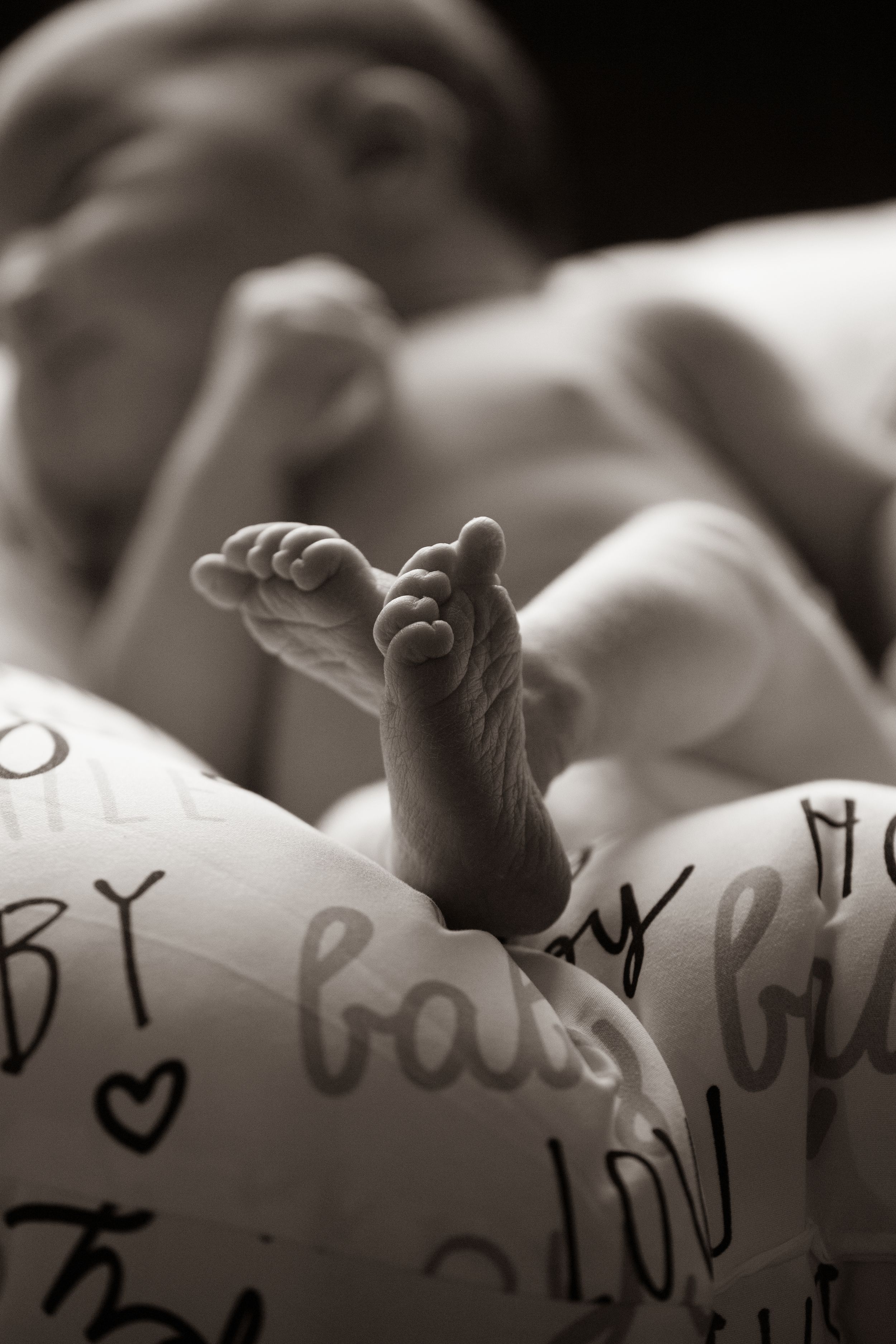 Artistic black and white photo of baby's foot against written text background.