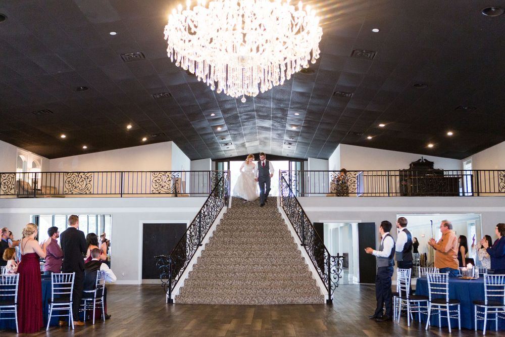 An elegant wedding venue interior with grand staircase and crystal chandelier.