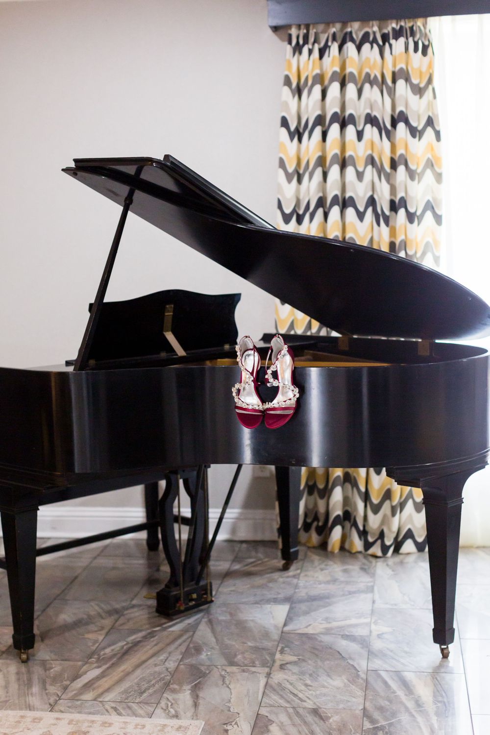 A black grand piano with chevron patterned curtains in the background.