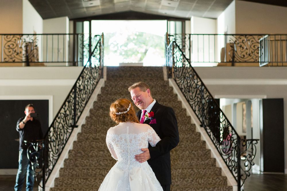 A couple dances on the grand staircase of their wedding venue.