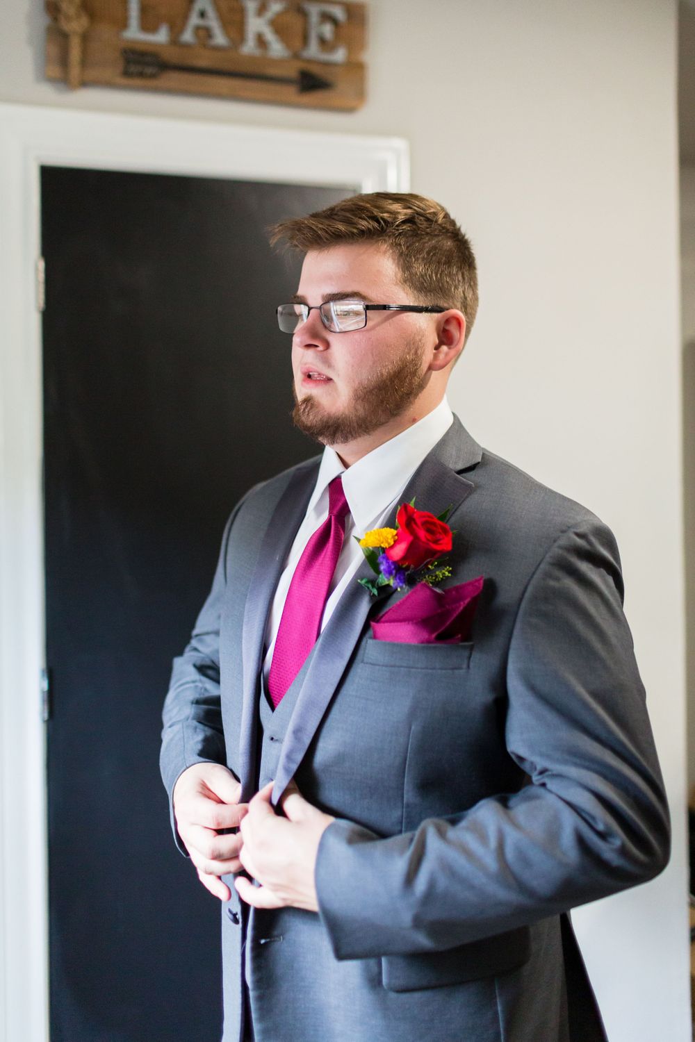 Formal attire with gray suit, burgundy tie, and colorful boutonniere.