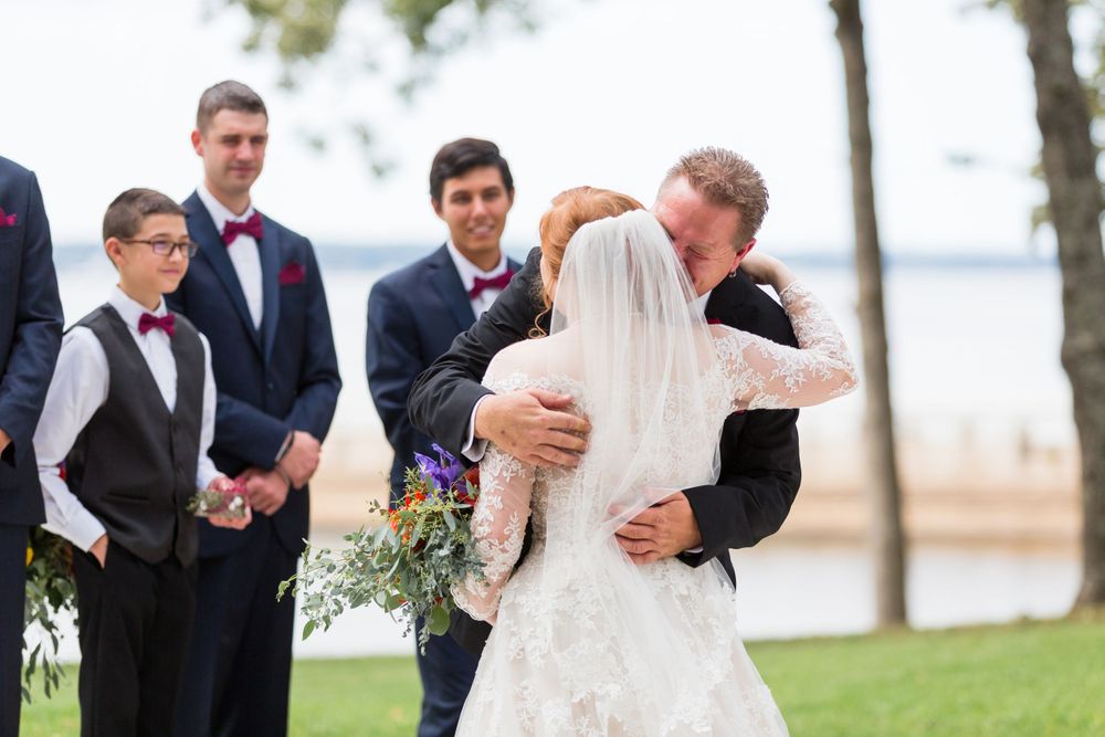 Wedding ceremony moment at waterfront venue with wedding party looking on.