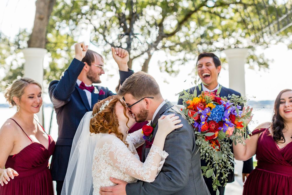 Joyful wedding celebration moment with vibrant bouquets under outdoor pergola.