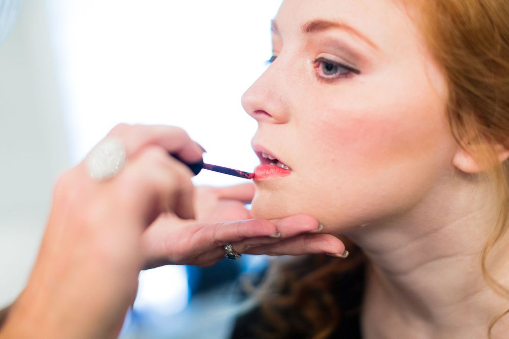 Makeup artist applying lipstick during beauty preparation.