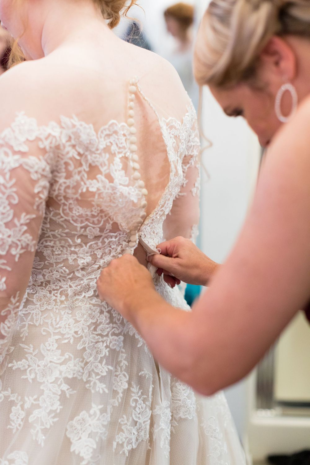 Detail of intricate lace wedding dress being buttoned up.