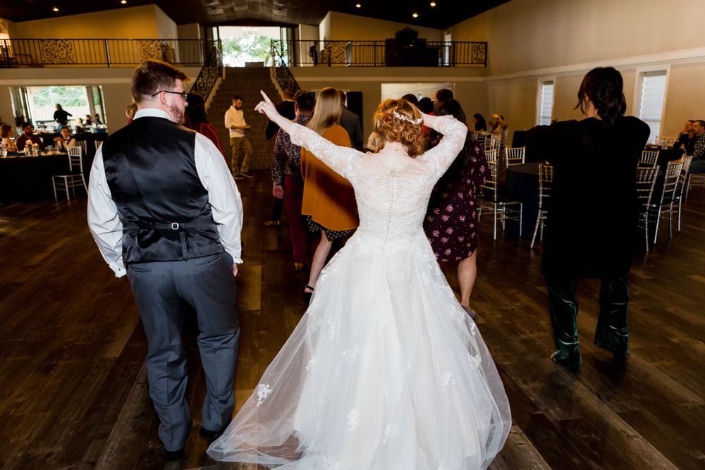 Newlyweds dancing and twirling on a wooden dance floor during their reception celebration.