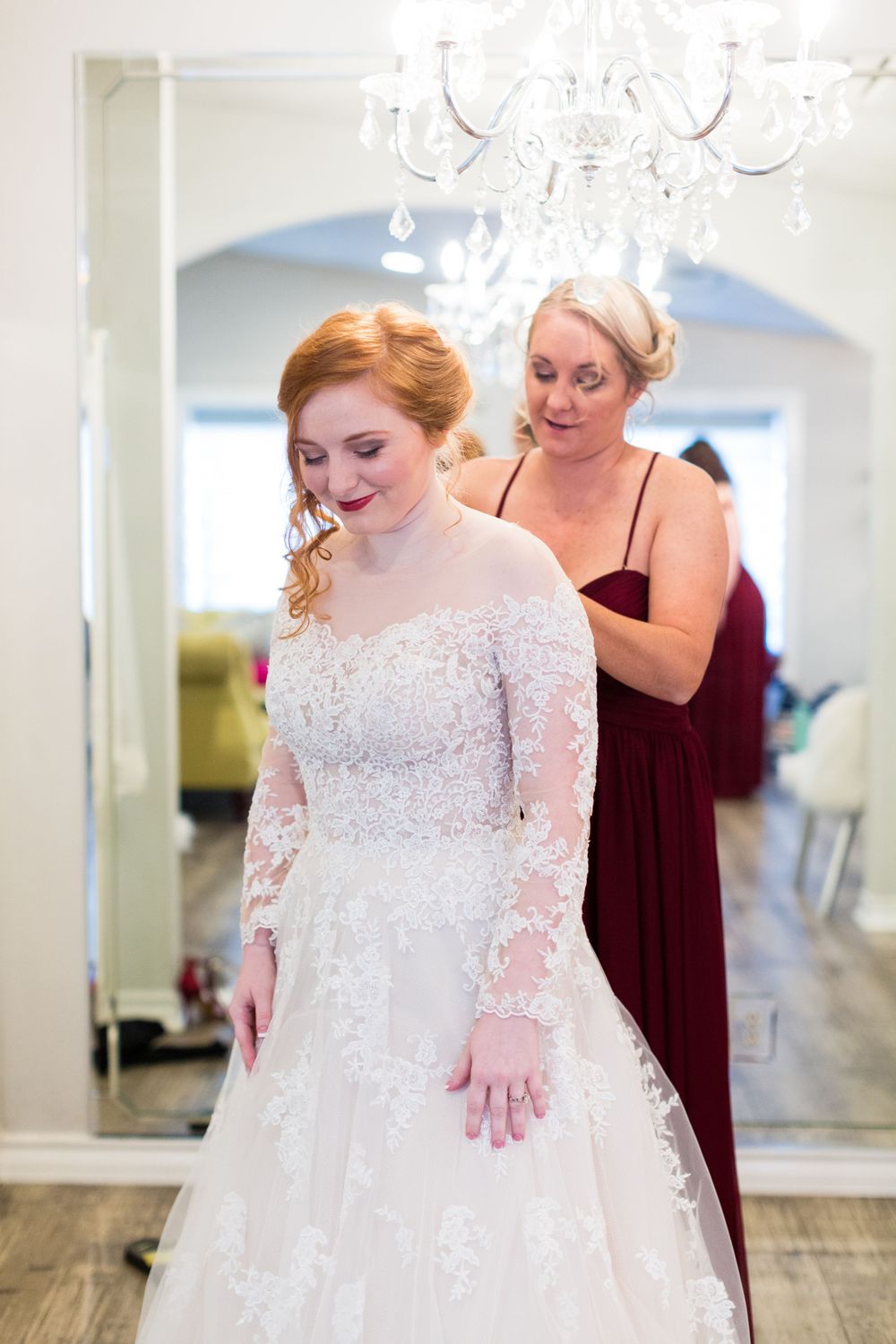 Elegant wedding dress fitting in a bridal boutique with chandelier.