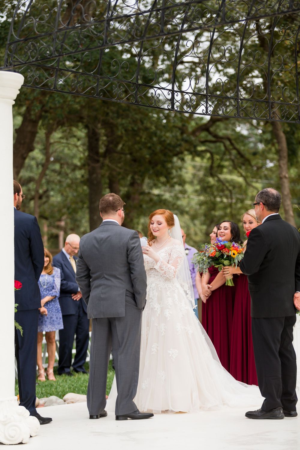 Wedding ceremony taking place on white aisle with guests and wedding party gathered.