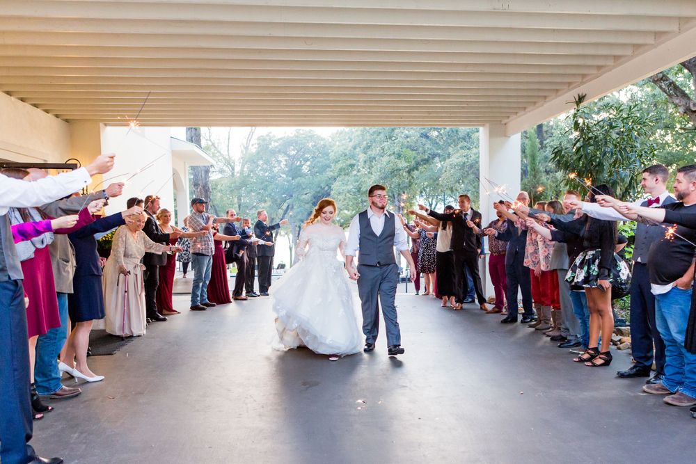 Couple walking through guest tunnel during wedding exit under white covered walkway.